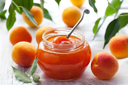 Apricot jam in jar and fresh fruits with leavesの写真素材