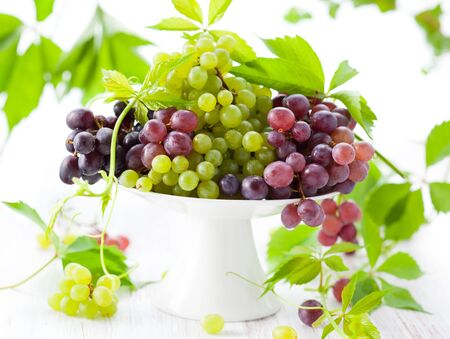 Various types of grapes with leaves on a cake standの写真素材