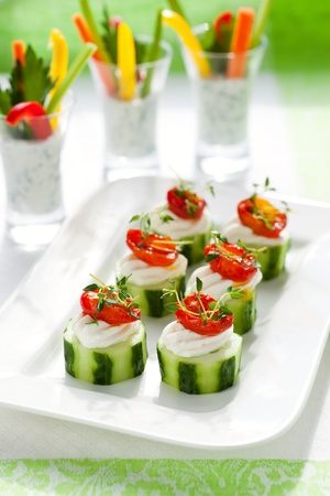 Holiday vegetable appetizers.Cucumbers with soft cheese and sun dried tomatoes and vegetable sticks with dipの写真素材