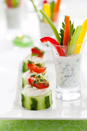 Holiday vegetable appetizers.Cucumbers with soft cheese and sun dried tomatoes and vegetable sticks with dipの写真素材