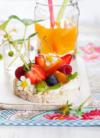 Multigrain rice cakes with berries, fruit and soft cheese for healthy breakfastの写真素材