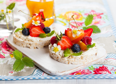 Multigrain rice cakes with berries, fruit and soft cheese for healthy breakfastの写真素材
