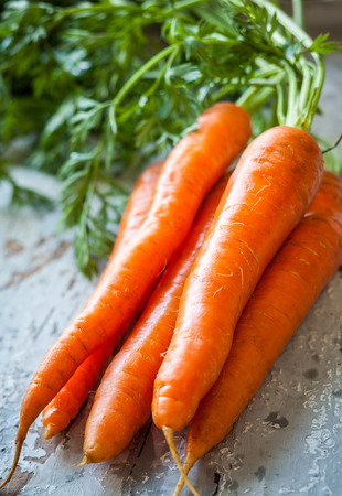 Fresh organic carrots on old wooden boardの写真素材