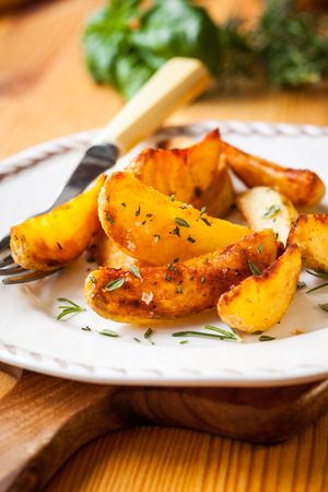 Roasted potato wedges with herbs and garlic on a plateの写真素材