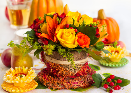 Festive table setting with basket of autumn flowers and pumpkinの写真素材