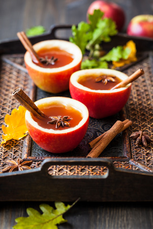 Apple cider with cinnamon sticks and anise star in apple cupsの写真素材