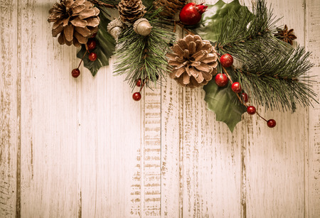 Christmas background with fir branches,pinecones and berries on the old wooden board