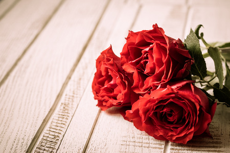 Red roses for holiday on the vintage wooden background.Toned image, selective focusの写真素材