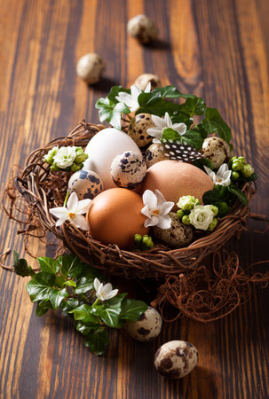 eggs in a nest with flowers,feathers on a wooden tableの写真素材