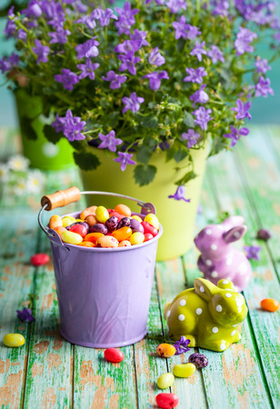 Easter rabbits and bucket with jelly beans on the vintage wooden tableの写真素材