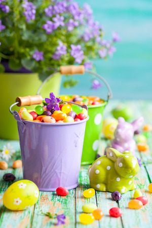 Easter rabbits and buckets with jelly beans on the vintage wooden tableの写真素材