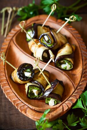 Eggplant rolls with pesto and feta on vintage wooden plate. Soft focusの写真素材