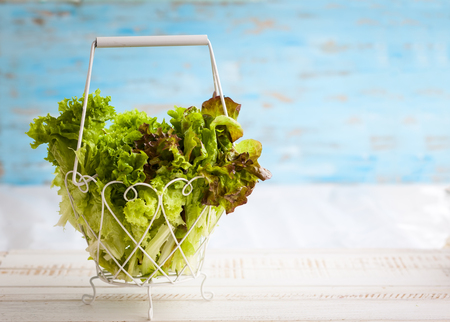 Various types of lettuce in a basket on the wooden tableの写真素材