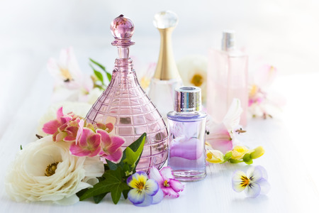 perfume and aromatic oils bottles surrounded by fresh flowerの写真素材