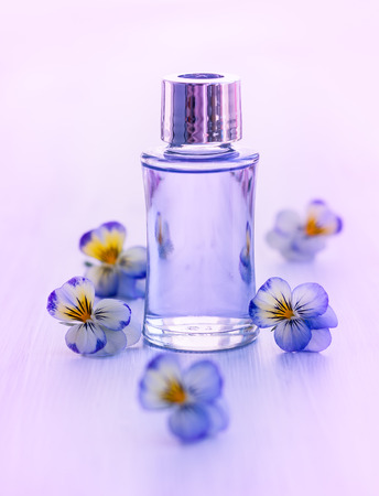 Bottle of essential aromatic oil surrounded by fresh flowerの写真素材