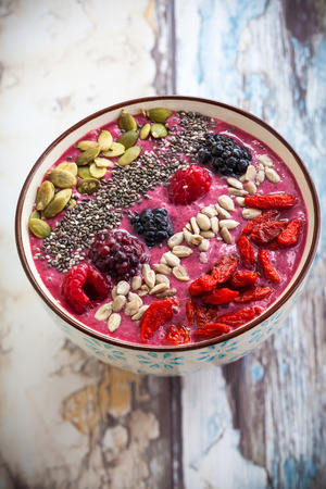 Breakfast berry smoothie bowl topped with goji berriesraspberry blackberry pumpkin sunflower and chia seeds.の写真素材