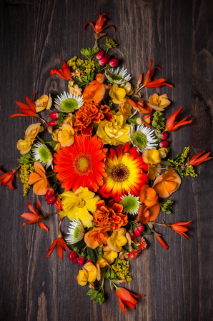 Autumnal flowers and berries on vintage wooden background. Top view with copy spaceの写真素材