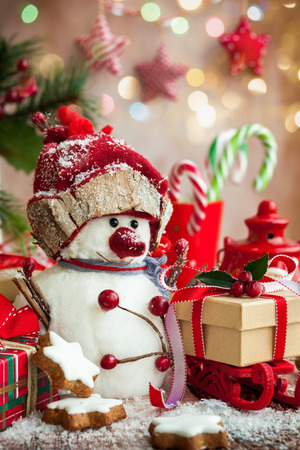 Snowman, Christmas presents and sweets  over wooden backgroundの写真素材