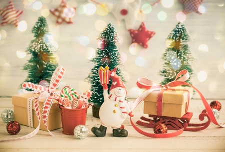 Snowman,gift boxes and decorative Christmas trees on the white wooden background. Vintage styleの写真素材