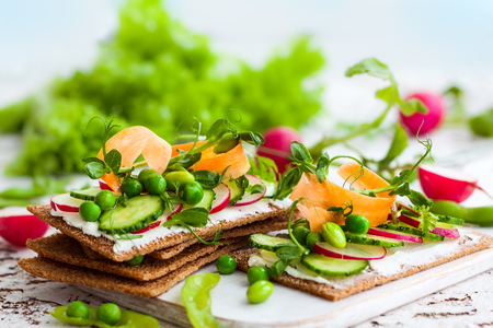 Healthy sandwiches with soft cheese and raw spring vegetables on crisp rye breadの写真素材