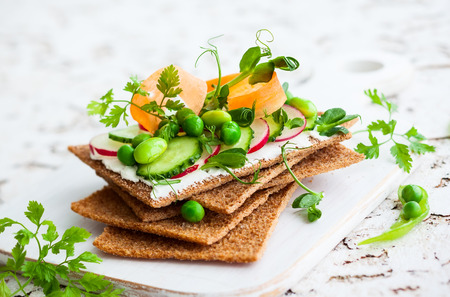 Healthy sandwiches with soft cheese and raw spring vegetables on crisp rye breadの写真素材
