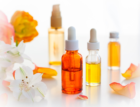 Bottles of essential aromatic oils and fresh flowersの写真素材