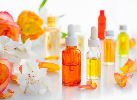 Bottles of essential aromatic oils and fresh flowersの写真素材