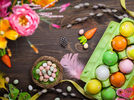 Easter decorations  with colorful eggs and sweet candy over wooden backgroundの写真素材