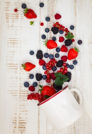 Fresh summer berries in vintage mug over wooden background,top viewの写真素材