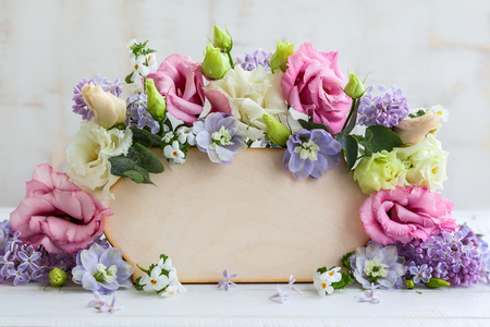 Festive frame with fresh flowers and wooden greeting cardの写真素材