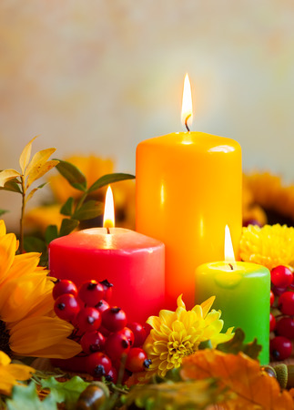 Autumn concept with burning colorful candles and flowersの写真素材
