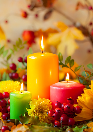 Autumn concept with burning colorful candles and flowersの写真素材