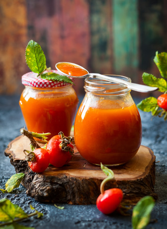 Rose hip jam in jar with fresh berries and leavesの写真素材