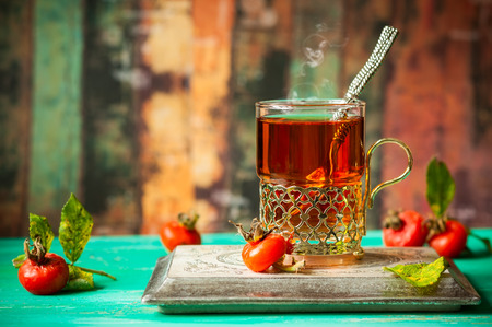 Glass of rosehip tea in a silver glass-holder and fresh berriesの写真素材