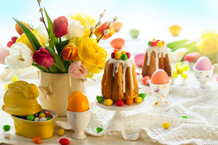 Easter table setting with spring flowers, cakes and easter eggs.の写真素材