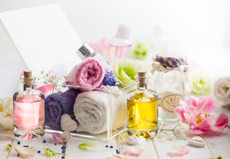 Bottles with essential aroma oil,towels different colors and fresh flowers  on white wooden background. Spa concept. Healthy cosmetic care. Place for textの写真素材