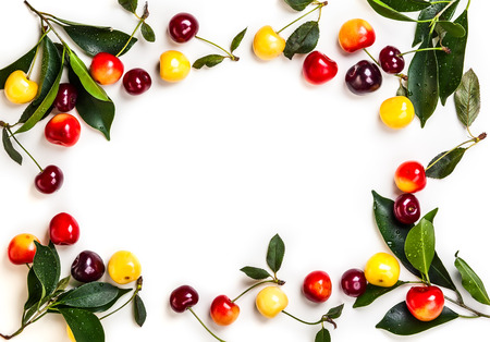 Assorted of fresh ripe cherry with green leaves on the old light background. Top view, copy spaceの写真素材