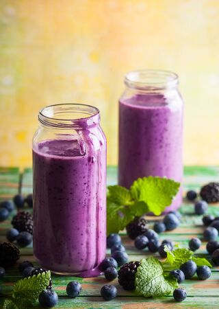 Fresh blackberry and blueberry smoothie in glass bottlesの写真素材