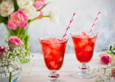 Refreshing summer drink with strawberry in  glasses and flowers in vase on wooden tableの写真素材