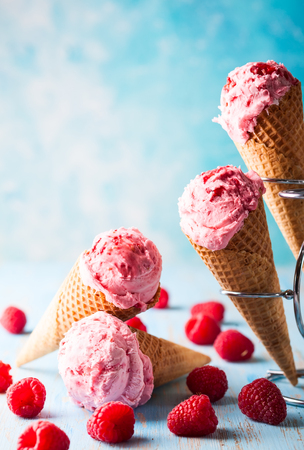 Ice cream with raspberry  in wafer cone on blue backgroundの写真素材