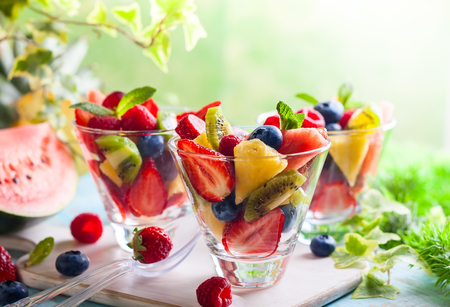 Healthy fresh fruit and berry salad with strawberries, raspberries, kiwi, pineapple, blueberries and watermelon on a table outdoorsの写真素材
