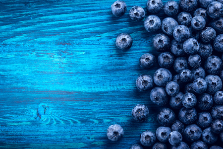 Fresh blueberry with drops of water on blue wooden background. Top view. Concept of healthy and dieting eatingの写真素材