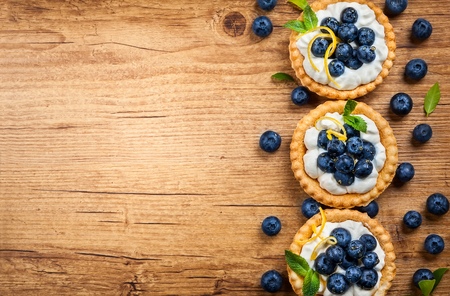 Delicious Blueberry tartlets with vanilla cream on the wooden background. Top view.の写真素材