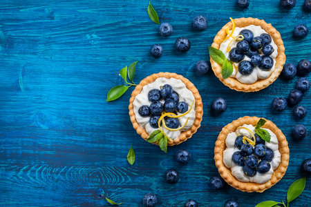 Delicious Blueberry tartlets with vanilla cream on  blue wooden background. Top view.の写真素材