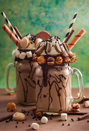 Chocolate milkshake with ice cream and with whipped cream, marshmallow, sweet popcorn, cookies, waffles, served in glass mason jar.の写真素材