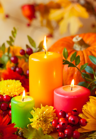 Autumn concept with burning colorful candles and flowersの写真素材