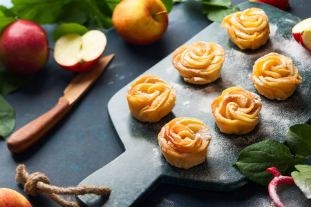 Apple Rose mini tarts with icing sugar on the stone cutting board.の写真素材