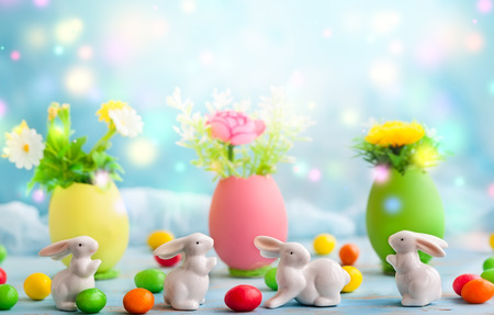 Easter decoration with spring flowers in colorful dyed eggs and white easter rabbits