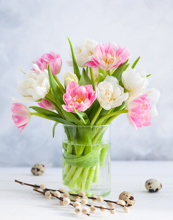 Easter bouquet of spring tulips and Easter decor on white wooden table. Easter concept with copy space.の写真素材