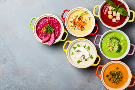 Variety of colorful vegetables cream soups in small pots. Top view. Concept of healthy eating or vegetarian food.の写真素材